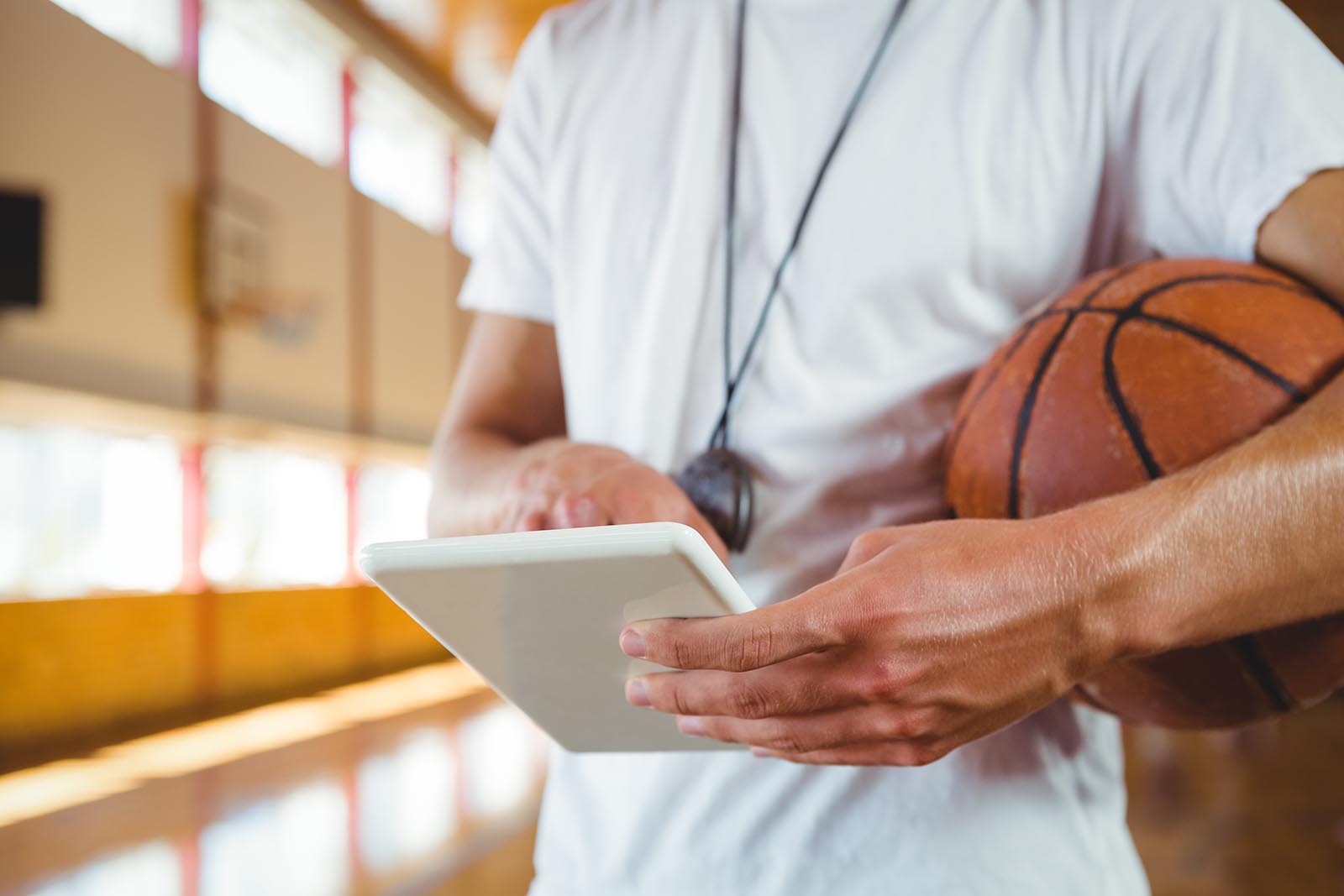 Midsection of male coach using digital tablet while standing in court